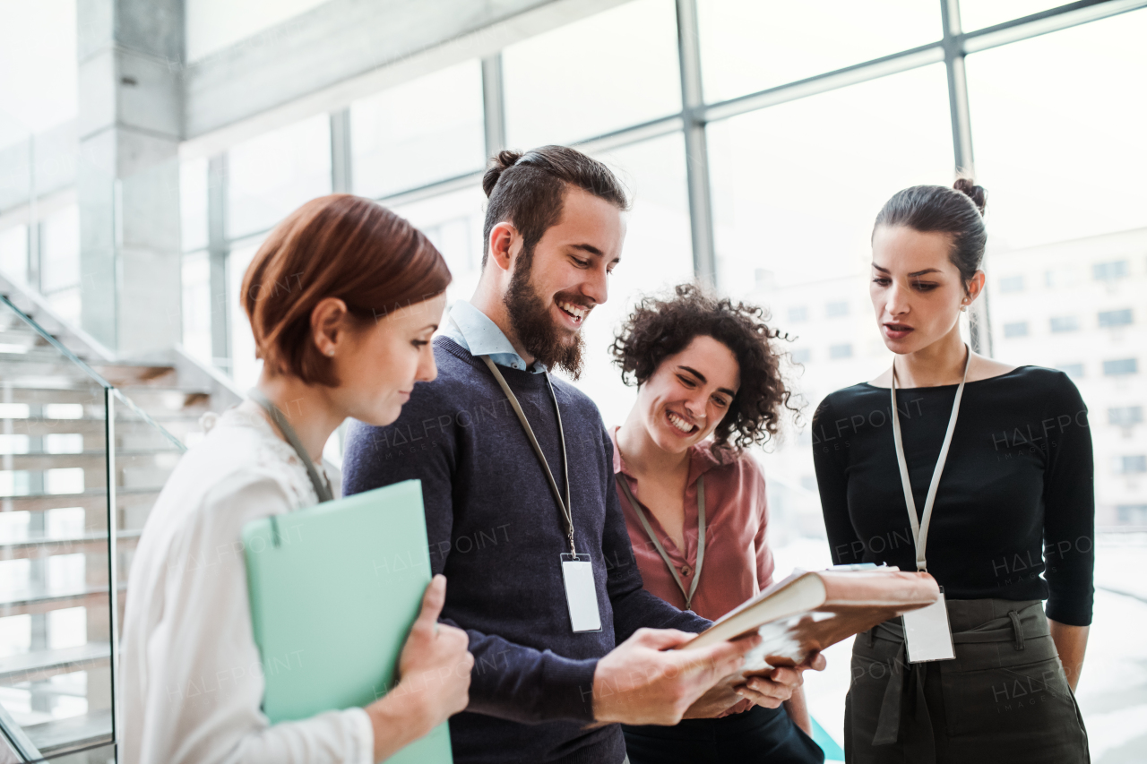 A group of young businesspeople standing near a staircase, talking.