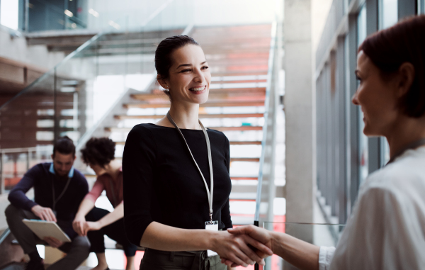 A group of young businesspeople standing on a staircase, shaking hands.