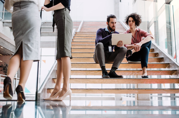 A group of young businesspeople sitting on a staircase, talking.