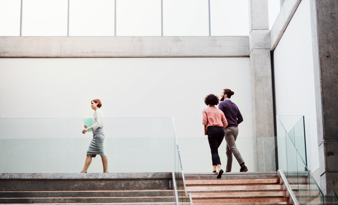 Three young businesspeople at work, walking up the stairs.