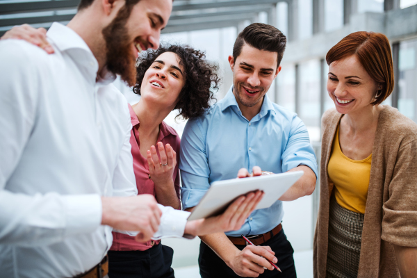 A group of young businesspeople standing near a staircase, talking.