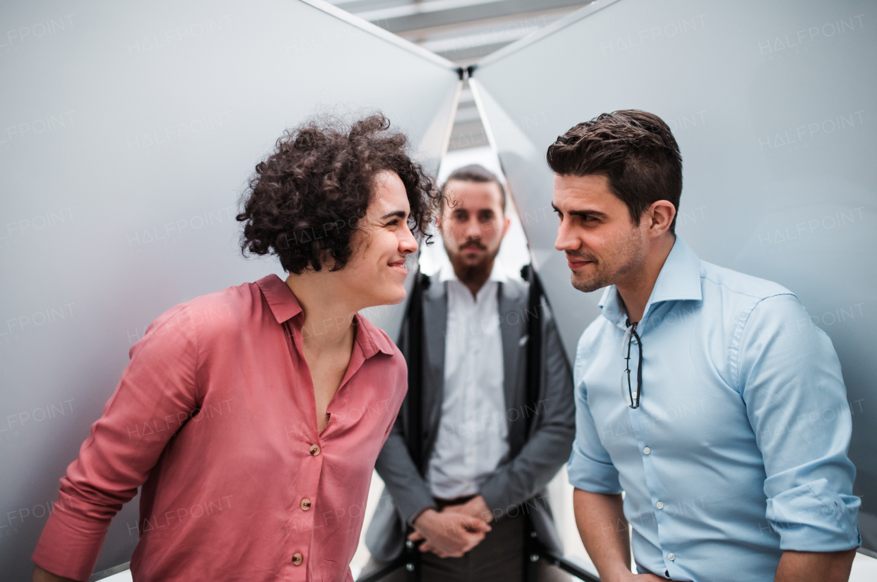 Young cheerful businesspeople standing in office, having fun.