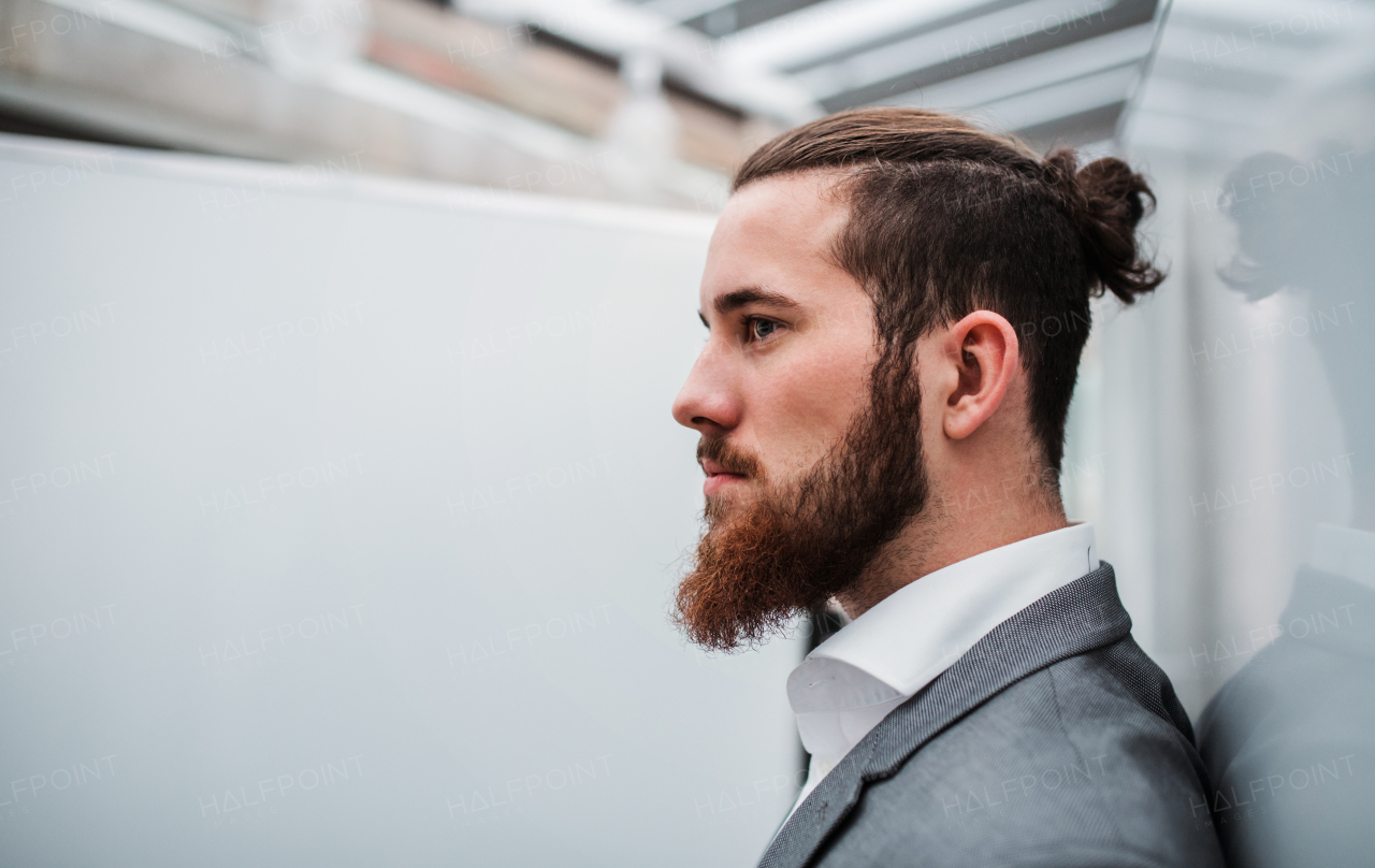 A side view portrait of young businessman standing in office. Copy space.