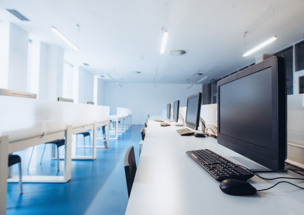 An interior of a modern spacious computer room for students in a library or office.