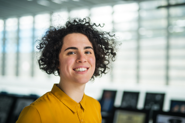 A portrait of a young student or businesswoman standing in room in a library or office.