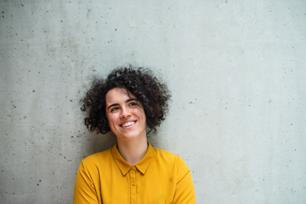 A portrait of a young student or businesswoman standing in room in a library or office.