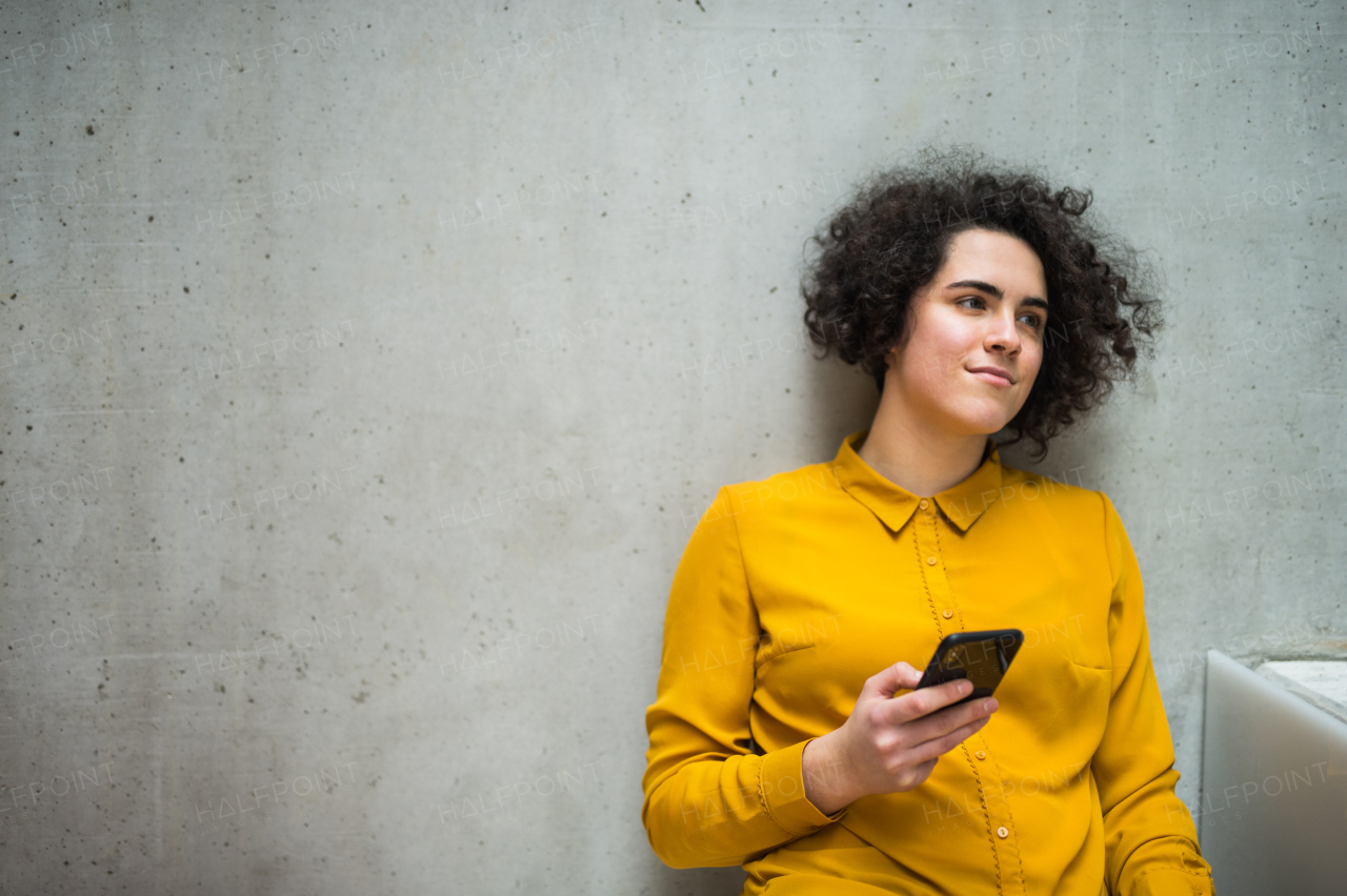 Portrait of a young student or businesswoman with smartphone in a library or office. Copy space.