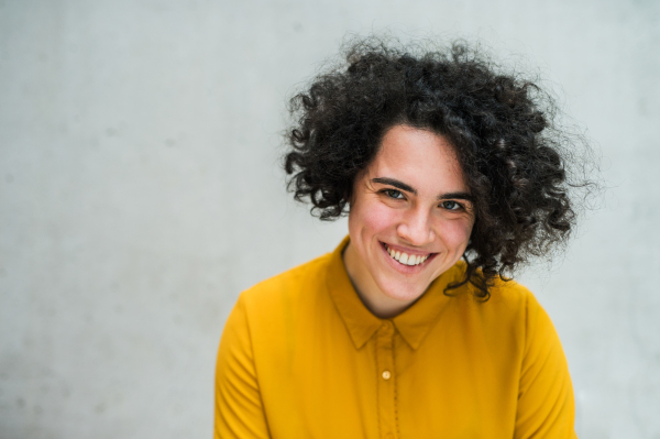 A portrait of a young student or businesswoman standing in room in a library or office.