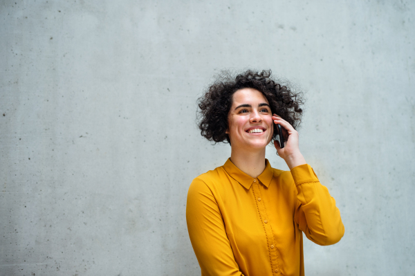 Portrait of a young student or businesswoman with smartphone in a library or office, making a phone call. Copy space.