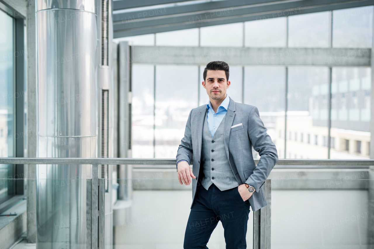 A front vire of portrait of young businessman indoors in an office. A close-up.