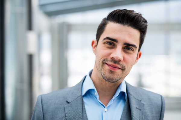 A portrait of young businessman standing indoors in an office. Copy space.