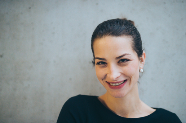 A portrait of young businesswoman standing in office, looking at camera.