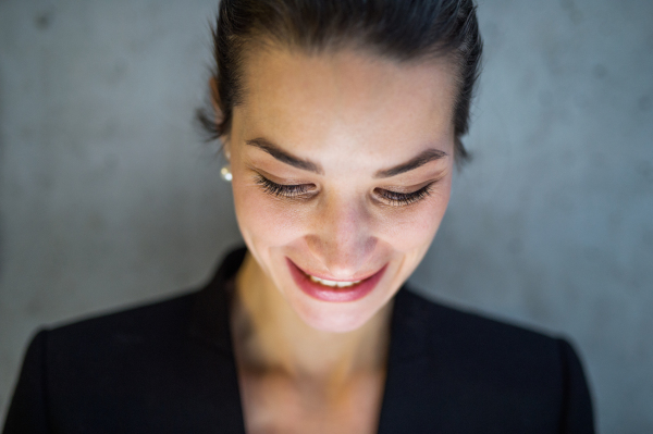 A close-up portrait of young businesswoman standing in office, looking down.