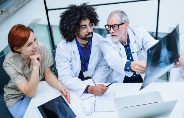 Top view of group of doctors looking at X-ray on medical conference, discussing issues.