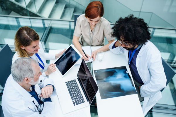 Top view of group of doctors looking at X-ray on medical conference, discussing issues.