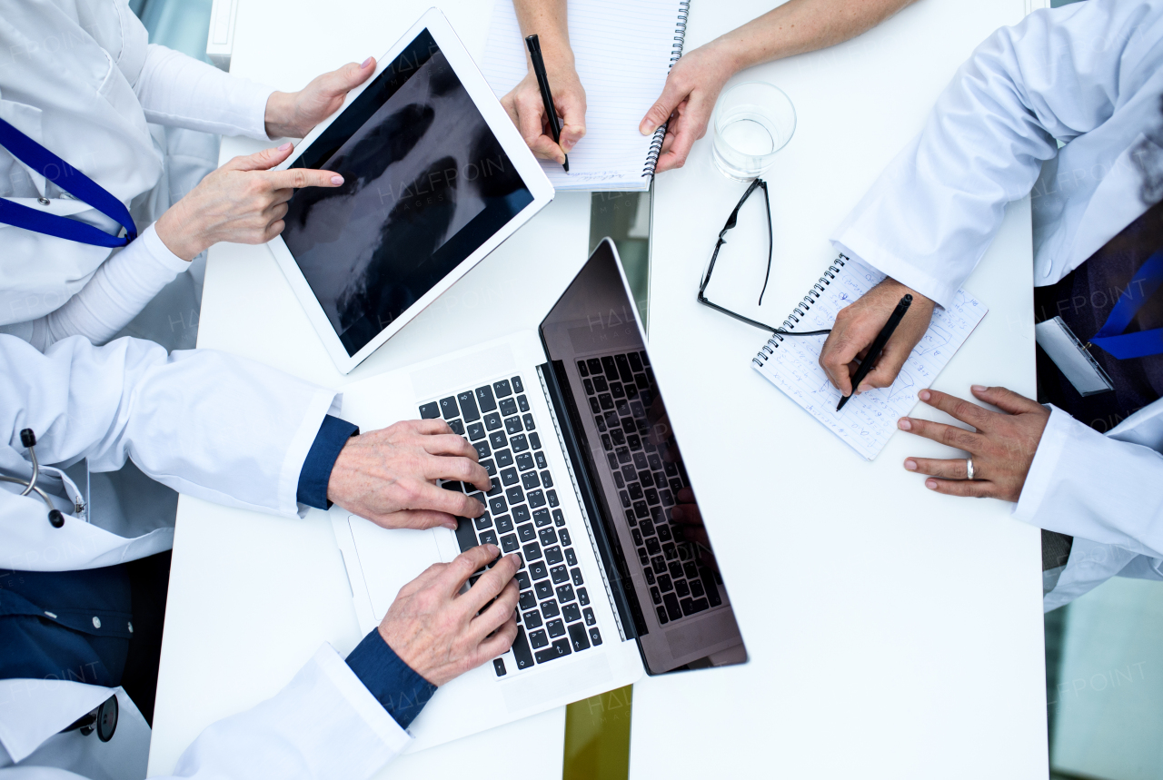 Top view of group of doctors looking at X-ray on medical conference, discussing issues.