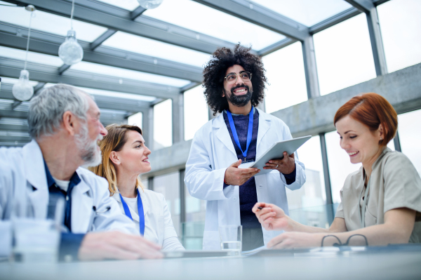 A group of doctors with tablet on conference, medical team discussing issues.