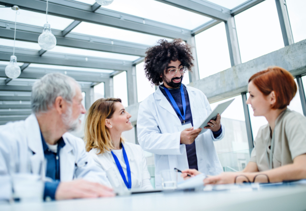 A group of doctors with tablet on conference, medical team discussing issues.