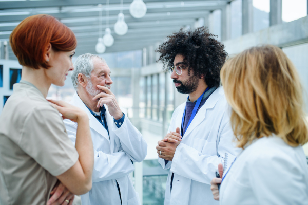 Group of thoughtful doctors standing on conference, medical team talking.