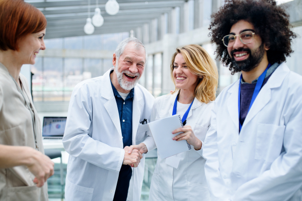 Group of doctors standing in corridor on medical conference, shaking hands.