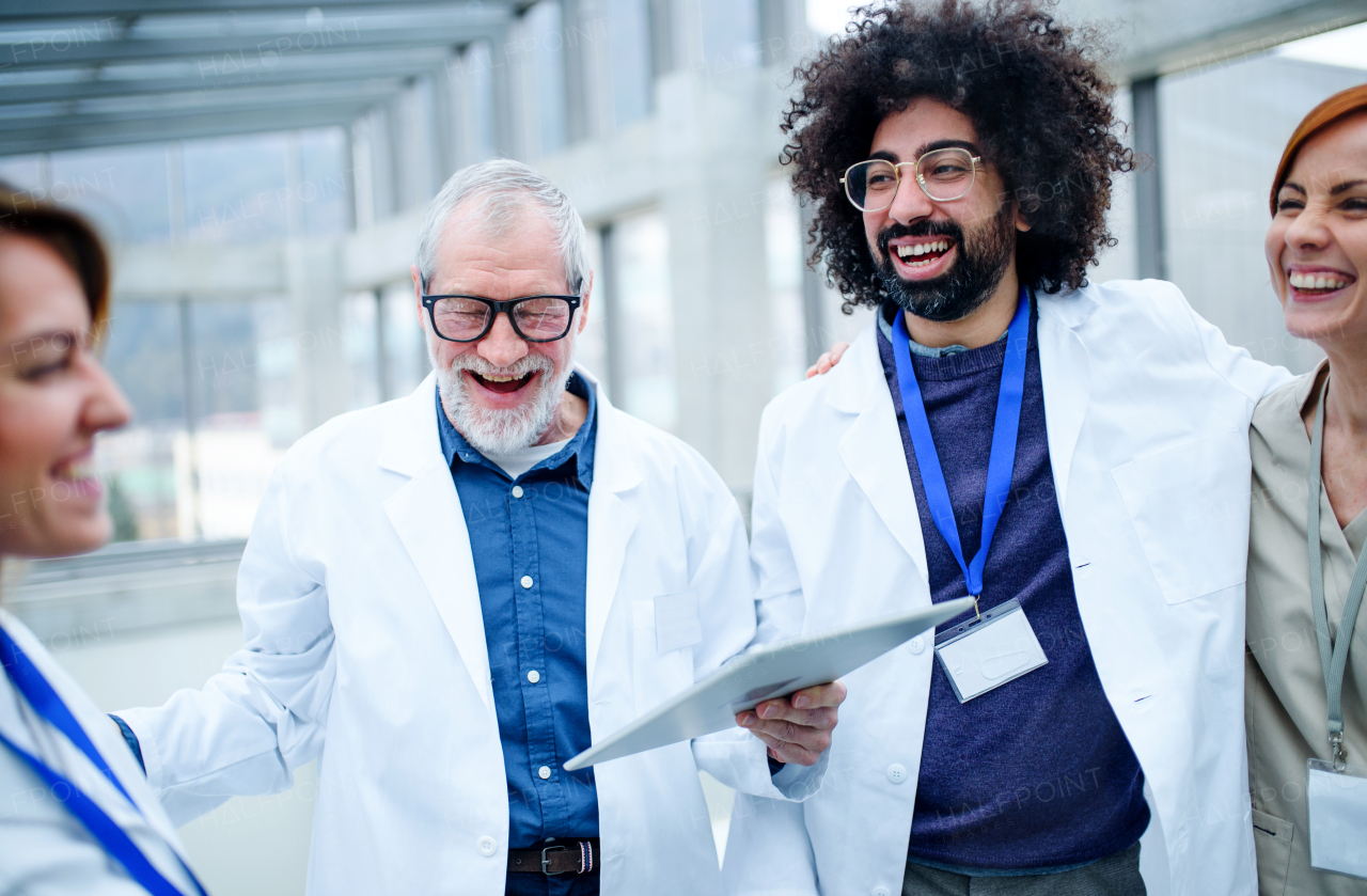 Group of doctors with tablet on conference, medical team laughing when discussing issues.