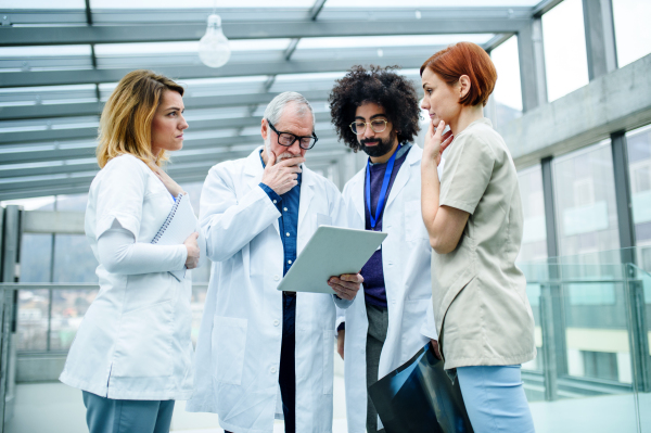 A group of doctors with tablet on conference, medical team discussing issues.