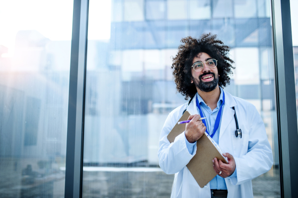 Portrait of cheerful male doctor standing in hospital. Copy space.