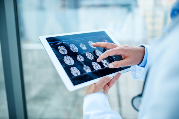 Midsection of unrecognizable doctor with tablet standing in hospital, working.