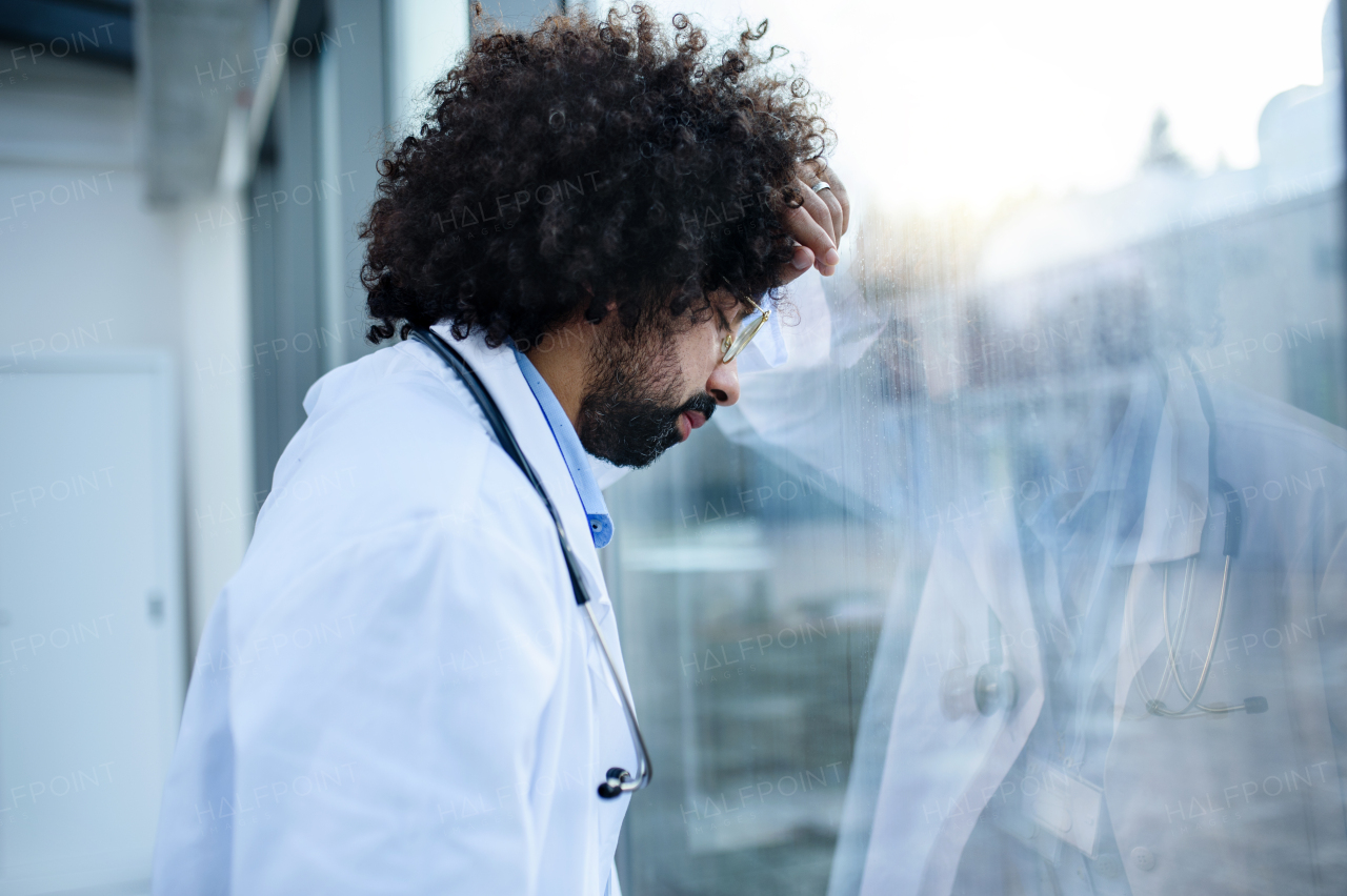 Worried and tired doctor standing in hospital, corona virus concept. Copy space.