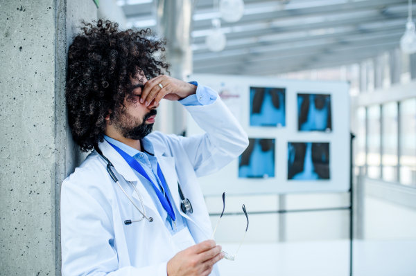 Worried and tired doctor standing in hospital, corona virus concept. Copy space.