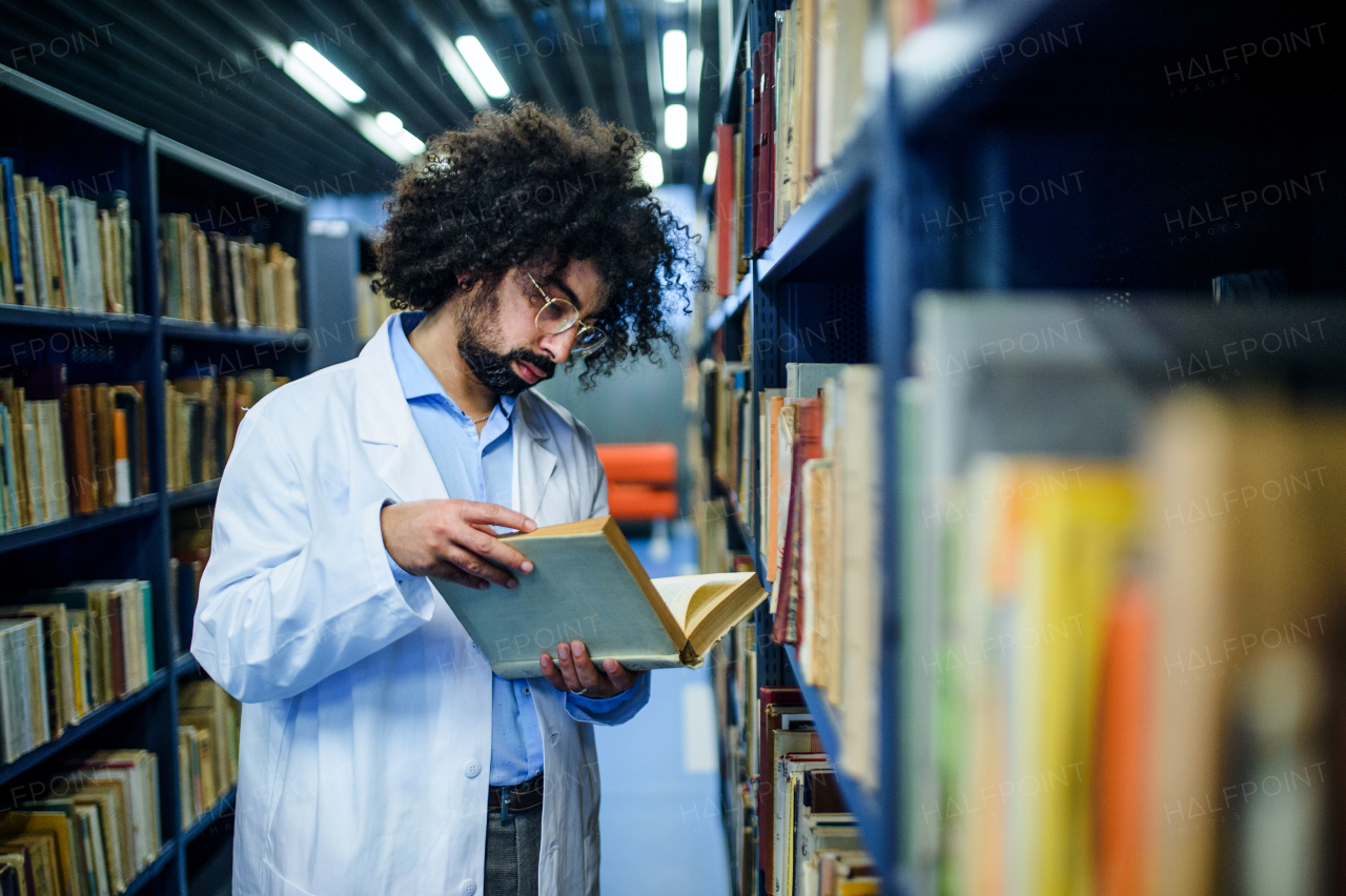 Portrait of male doctor standing in library, studying information about corona virus.