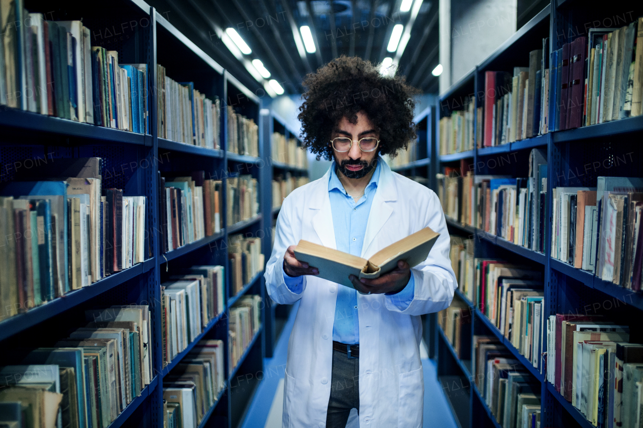 Portrait of male doctor standing in library, studying information about corona virus.