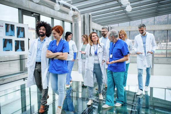 Front view of group of doctors walking in corridor on conference, talking.