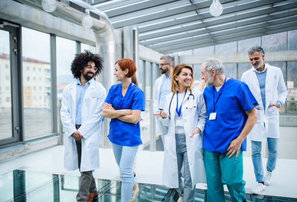 Front view of group of doctors walking in corridor on conference, talking.