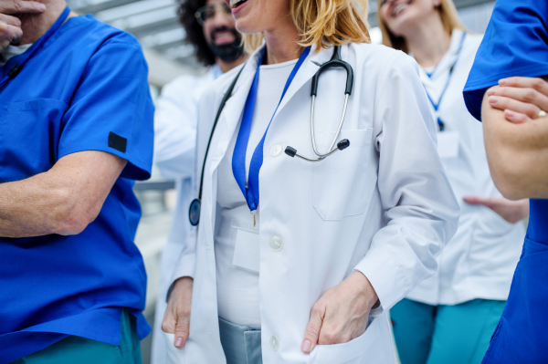 Group of unrecognizable doctors walking in corridor on conference, talking.