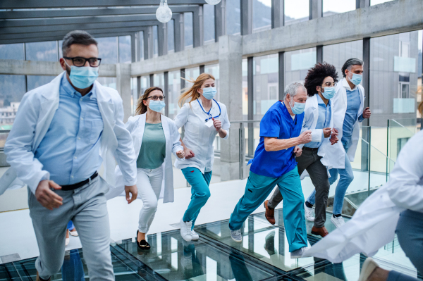 Group of doctors in hurry running in corridor of hospital, emergency concept.