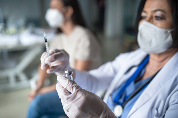 Portrait of senior woman doctor with syringe in hospital, coronavirus and vaccination concept.