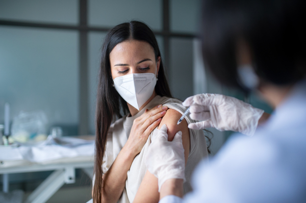 Mid woman with face mask getting vaccinated in hospital, coronavirus and vaccination concept.