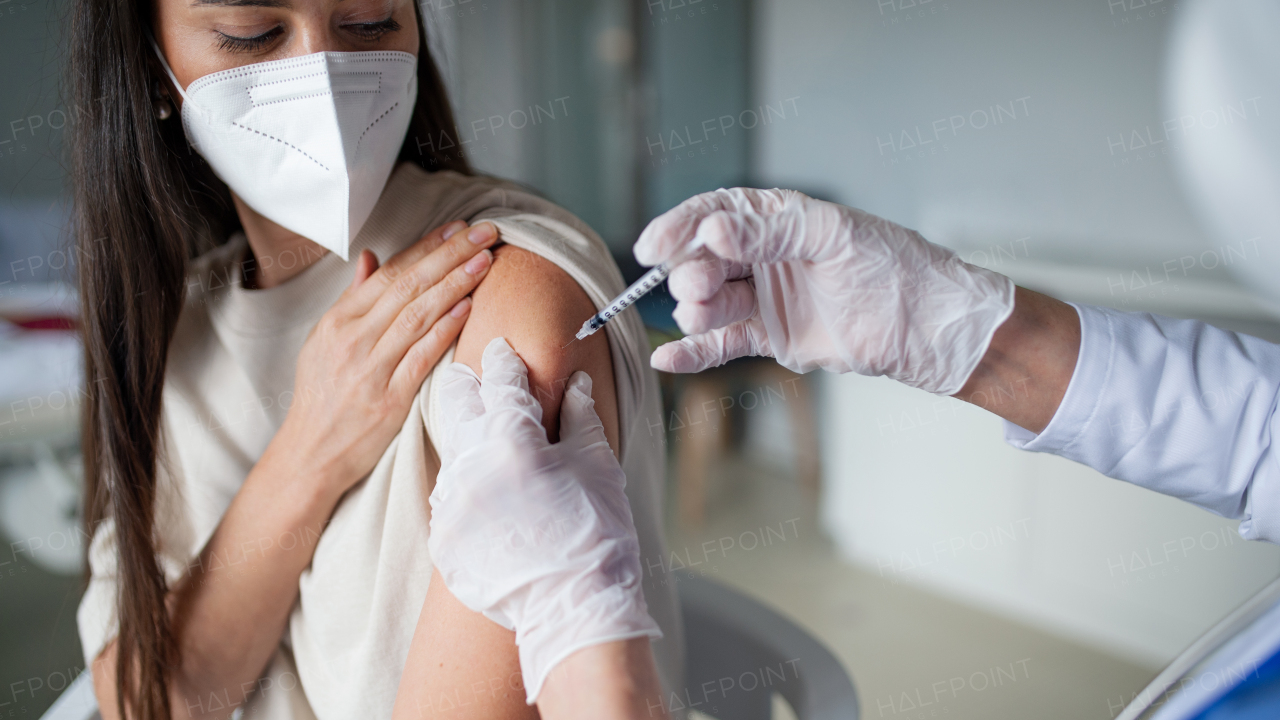 Mid adult woman with respirator getting vaccinated in hospital, coronavirus and vaccination concept.