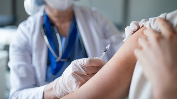 Midsection of unrecognizable woman getting vaccinated in hospital, coronavirus and vaccination concept.