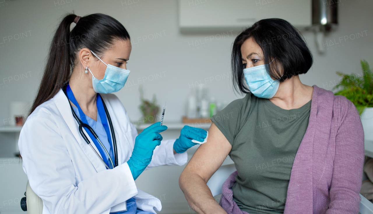 Senior woman with face mask getting vaccinated in hospital, coronavirus and vaccination concept.