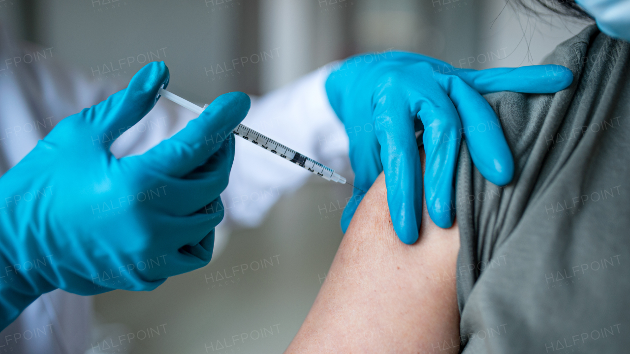 Midsection of unrecognizable woman getting vaccinated in hospital, coronavirus and vaccination concept.