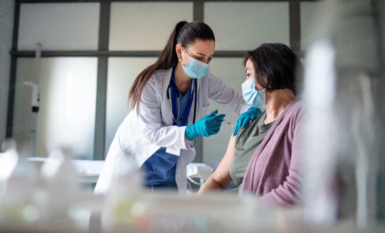 A senior woman getting vaccinated in hospital, coronavirus and vaccination concept.