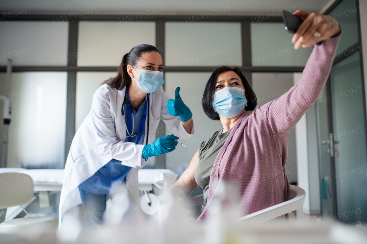 A senior woman taking selfie when getting vaccinated in hospital, coronavirus and vaccination concept.