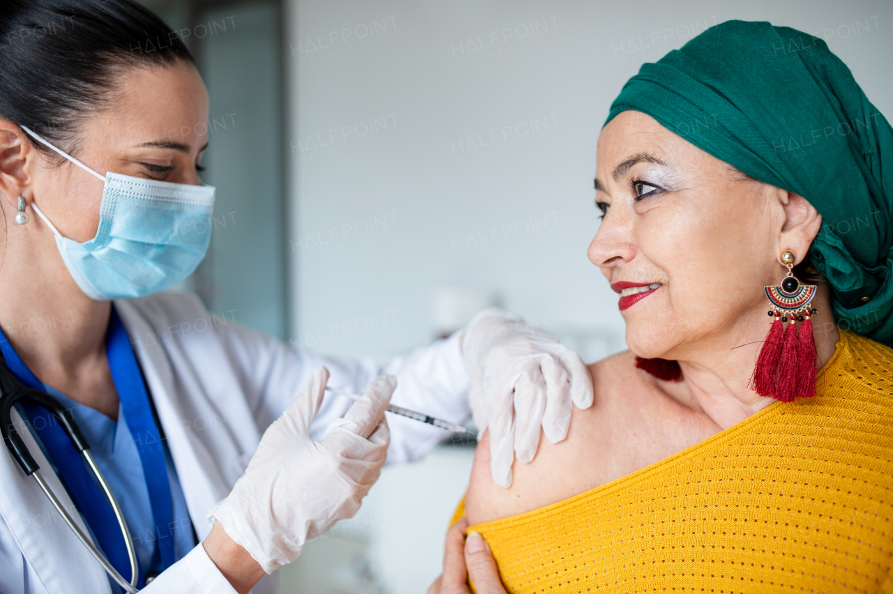 Happy woman with smartphone getting vaccinated in hospital, coronavirus and vaccination concept.