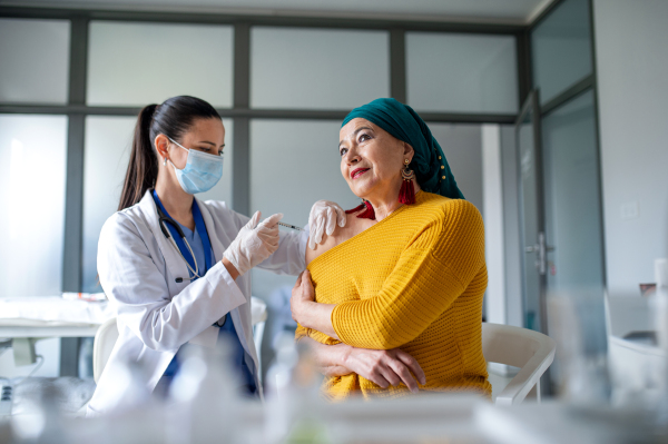 Happy woman with smartphone getting vaccinated in hospital, coronavirus and vaccination concept.