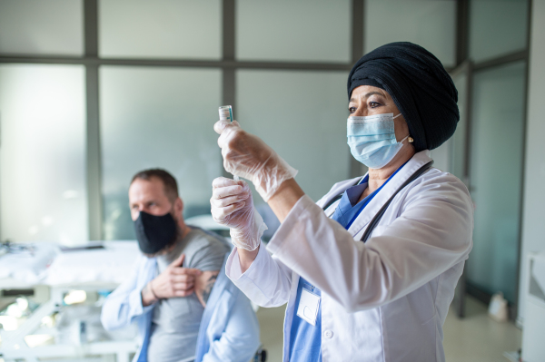 Portrait of senior woman doctor with syringe in hospital, coronavirus and vaccination concept.