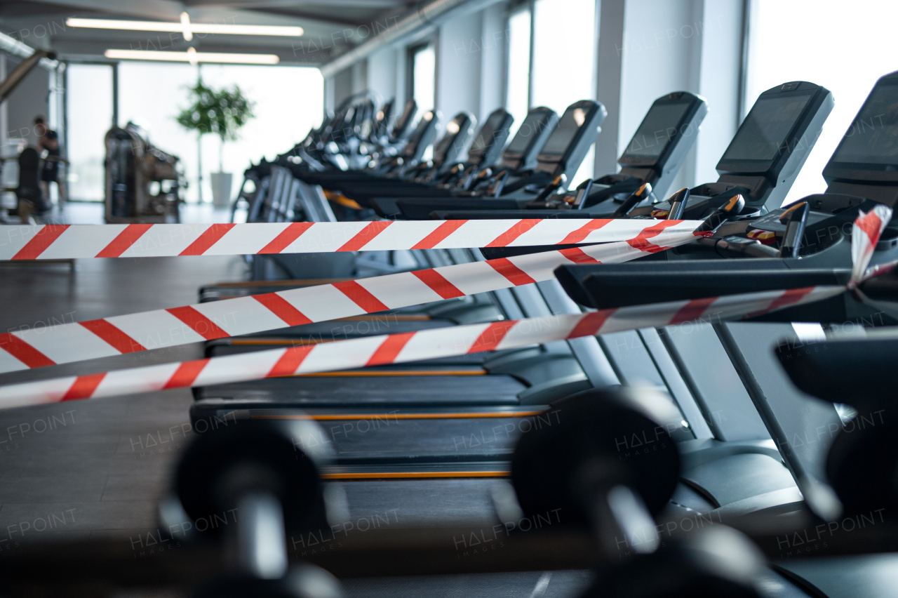 A marking tape on treadmill machines in gym, safe distance and coronavirus concept.