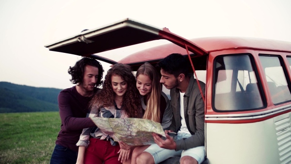 Young friends on a roadtrip through countryside, looking at a map. Slow motion.