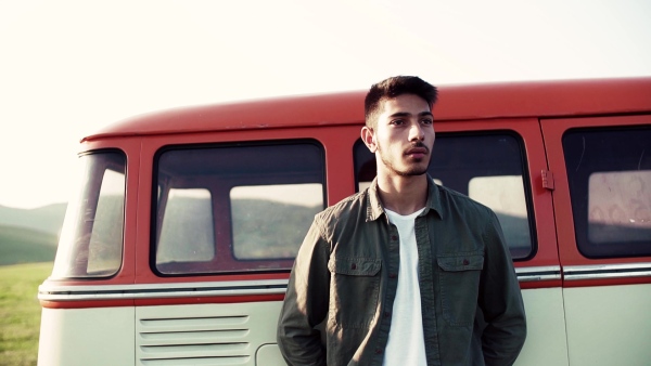 A young boy standing by a car on a roadtrip through countryside. Slow motion.